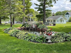 A well-maintained garden with a pond, surrounded by lush greenery and a gazebo. - Spacious 3BR Retreat | Perfect for Families! (Indian River)