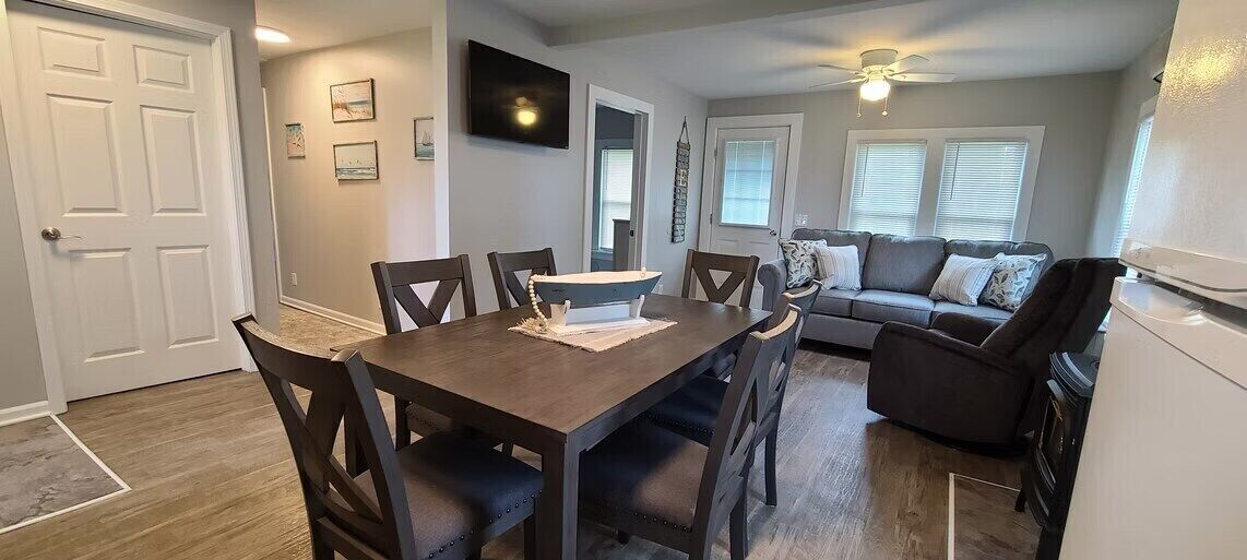 Un coin repas avec une table et des chaises en bois, un canapé et un ventilateur de plafond.