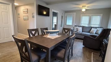 Un coin repas avec une table et des chaises en bois, un canapé et un ventilateur de plafond.