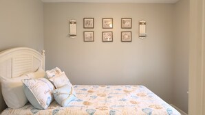 Ein Schlafzimmer mit Bett, Kissen und Wandbildern.