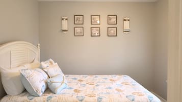 A bedroom with a bed, pillows, and wall-mounted artwork.