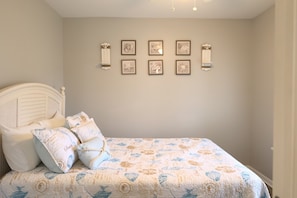 A bedroom with a bed, pillows, and wall-mounted artwork. - Spacious 3BR Retreat | Perfect for Families! (Indian River)