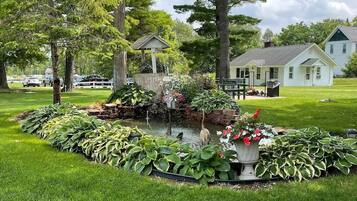A well-maintained garden with a pond, surrounded by lush greenery and a gazebo.