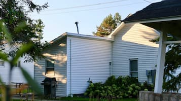 A white house with a chimney, a covered porch, and a well-maintained garden.