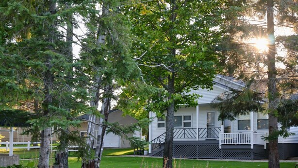 A residential house with a front porch, surrounded by trees and a well-maintained lawn. - Cozy Riverfront Getaway | 1BR + Sleeper Sofa (Indian River)