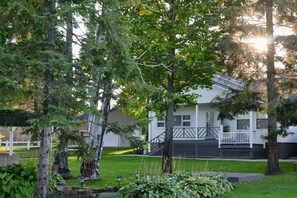 A residential house with a front porch, surrounded by trees and a well-maintained lawn.