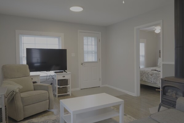 A living room with a flat-screen TV, a beige sofa, a white coffee table, and a fireplace.