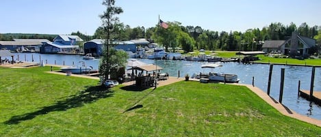 A marina with boats docked, a flagpole with an American flag, and buildings in the background.