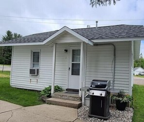 A single-story house with a front porch, a door, and a small attached garage with a grill. - Cozy Riverfront Getaway | 1BR + Sleeper Sofa (Indian River)
