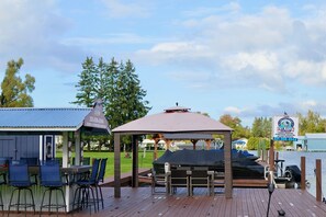 A wooden deck with outdoor seating, a gazebo, and a view of a lake.
