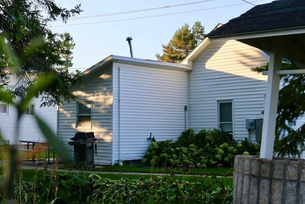 A white house with a chimney, a covered porch, and a well-maintained garden.