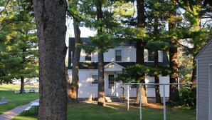 A house with a front yard, a picnic table, and a swing set. - Charming 2BR Cabin | River Views & Outdoor Space (Indian River)