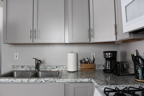 A kitchen with a granite countertop, stainless steel sink, and a gas stove.