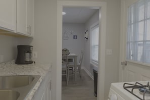 A kitchen with a sink, stove, and dining area with chairs and a table.