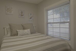 A bedroom with a bed, striped bedding, and three wall-mounted nautical-themed artworks. - 1BR Hideaway | Steps from Indian River (Indian River)