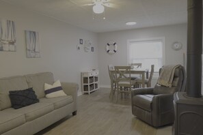 A living room with a sofa, a dining table with chairs, a fireplace, and artwork on the walls.