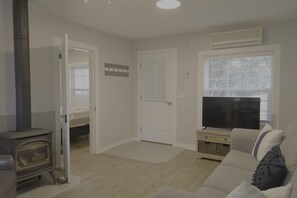 A living room with a sofa, a television, a fireplace, and a door leading to another room.