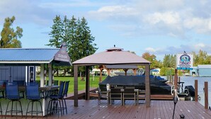 A wooden deck with outdoor seating, a gazebo, and a view of a lake. - 1BR Hideaway | Steps from Indian River (Indian River)