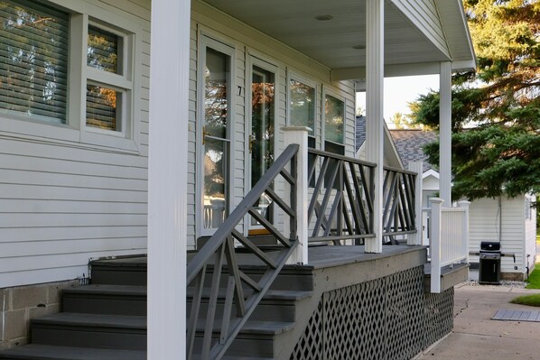 A white house with a covered porch and a set of stairs leading to the entrance.