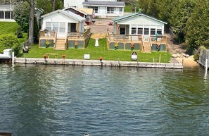 A lakeside cabin with a dock, a deck, and a small porch.