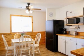 A compact kitchen with a black refrigerator, white cabinets, a wooden countertop, and a ceiling fan. - Riverside Escape | Perfect for Families & Friends (Indian River)