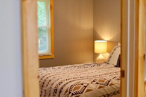 A bedroom with a bed, a window with blinds, and a bedside lamp. - Riverside Escape | Perfect for Families & Friends (Indian River)
