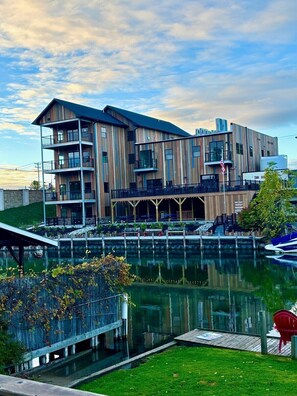 A multi-story building with a waterfront patio, outdoor seating, and a dock with boats. - Riverside Escape | Perfect for Families & Friends (Indian River)