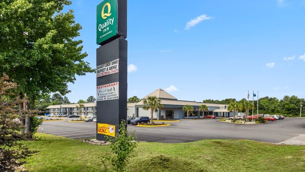 A Quality Inn sign, a parking lot, and a building with a flag.
