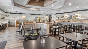 A spacious restaurant with multiple dining areas, a bar, and a kitchen visible in the background.