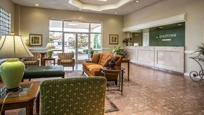 A lobby with a reception desk, seating area, and large windows.