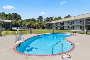 A swimming pool with a red brick border, a lifeguard chair, and a fence.