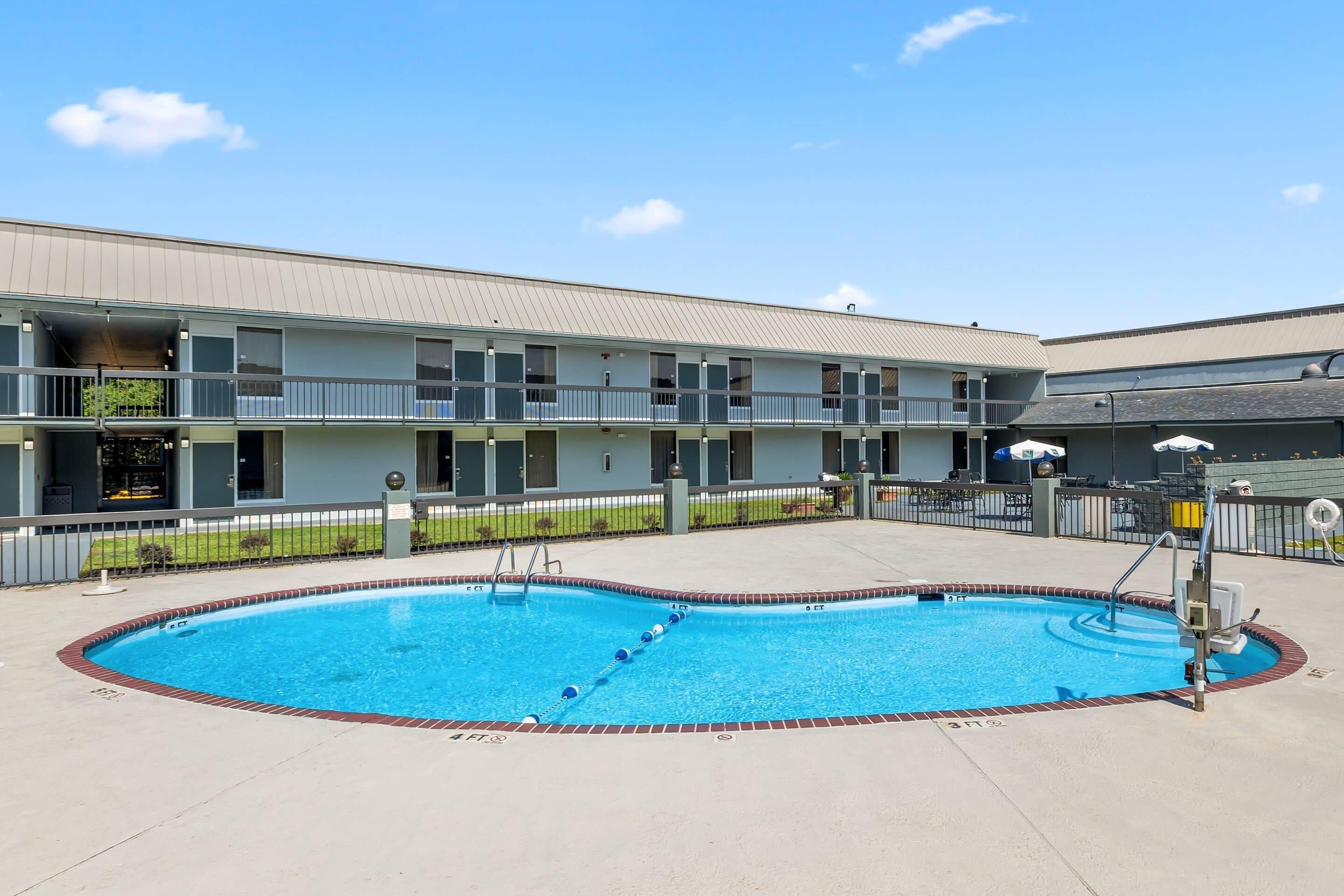 Un motel con piscina, área cercada y un edificio con varios balcones.