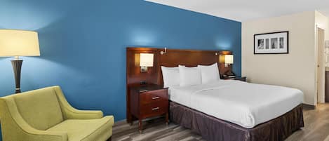 A hotel room with a bed, bedside tables, a lamp, a chair, and a picture on the wall.