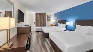 Une chambre d’hôtel avec deux lits, un bureau, une télévision et un grand miroir.