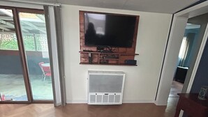 Una sala de estar con una televisión de pantalla plana montada en la pared, una chimenea debajo y una alfombra estampada en el suelo.