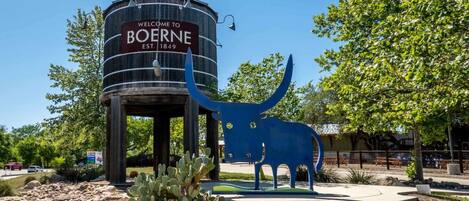 A water tower with a sign reading "Welcome to Boerne, Est. 1849" and a blue sculpture of a bull.