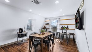 A modern kitchen with a wooden table and chairs, a microwave, and a coffee machine.