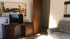 Ένα σαλόνι με ένα ξύλινο γραφείο, μια τηλεόραση και έναν καναπέ.