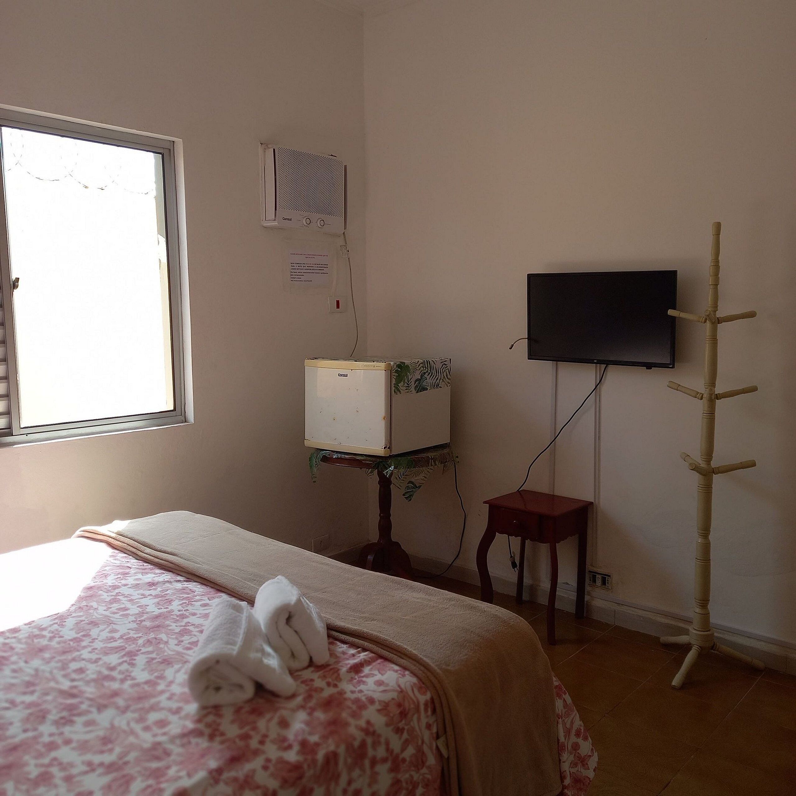 Ein Schlafzimmer mit Bett, Fernseher, Heizung und Fenster.