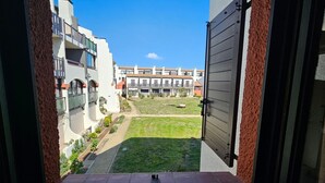 Un patio con césped, una piscina pequeña y un edificio con varios balcones.