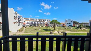 Zona residencial con edificios de varios pisos, un patio con césped y un cielo azul despejado.
