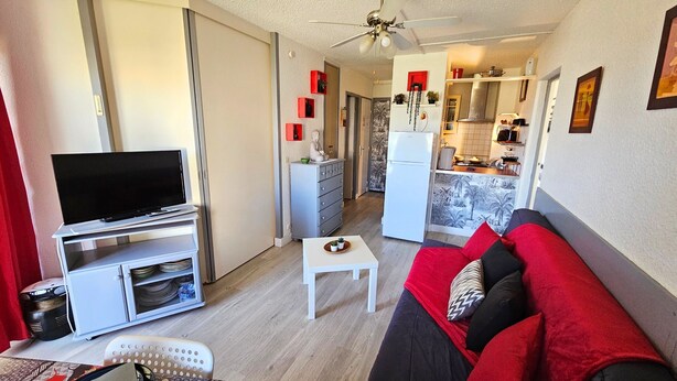 Un espacio habitable compacto con televisor, sofá y kitchenette.