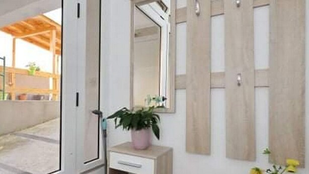 A modern bathroom with a wooden vanity, a mirror, and a potted plant.