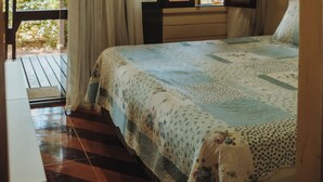 Ein Schlafzimmer mit einem Bett, einem Fenster mit Vorhängen und einer Holzbalkendecke.