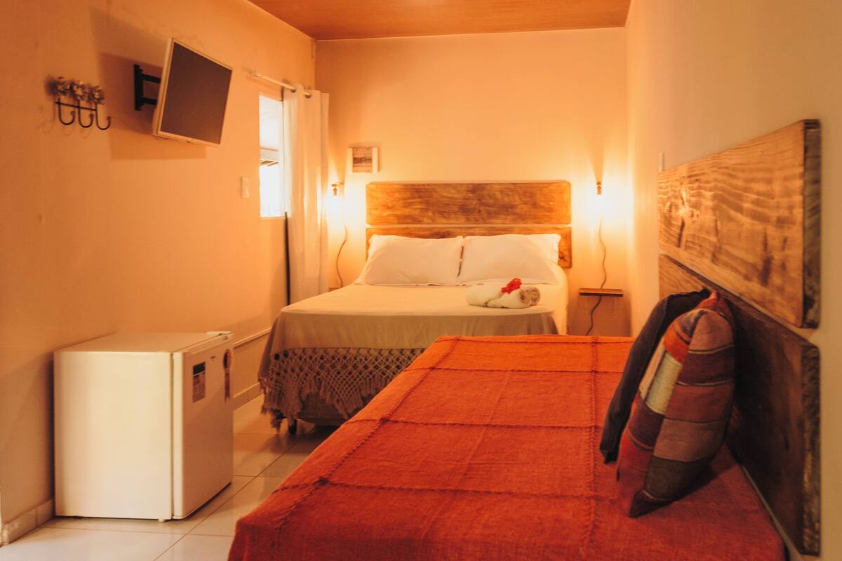 Una camera da letto con un letto, un piccolo frigorifero e un soffitto in legno.