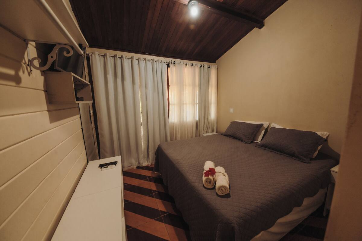 Una camera da letto con un letto, tende, un comodino e una mensola a parete.