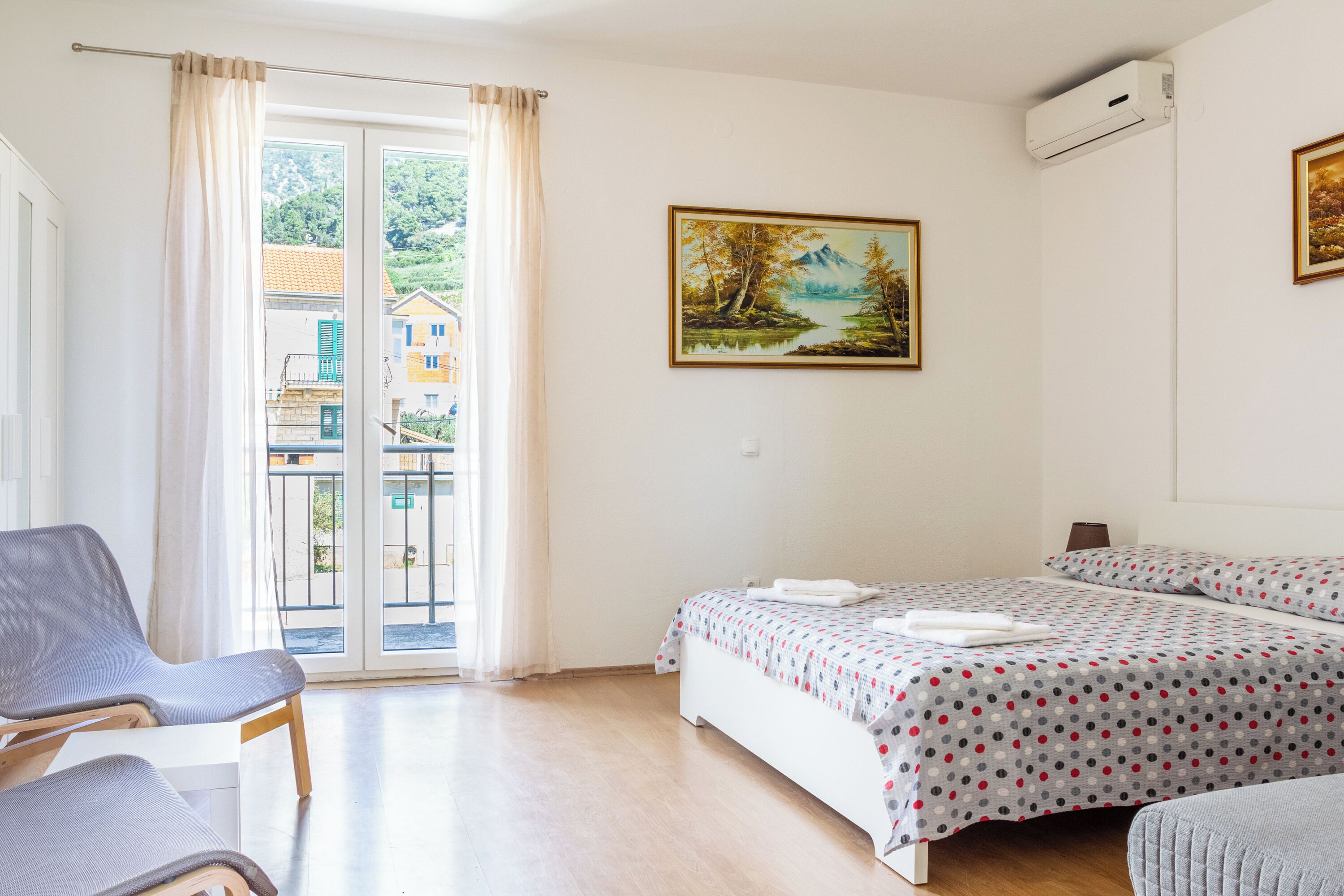 Un dormitorio con cama, una silla y una ventana con cortinas.