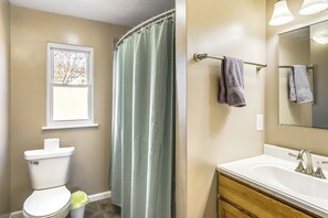 A bathroom with a toilet, sink, mirror, and shower curtain.