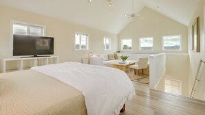 Une chambre spacieuse avec un grand lit, une télévision et un ventilateur de plafond.