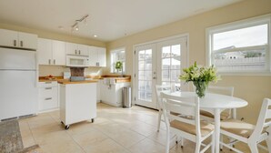 Une cuisine moderne avec des meubles blancs, un four à micro-ondes et un coin repas comprenant une table et des chaises blanches.